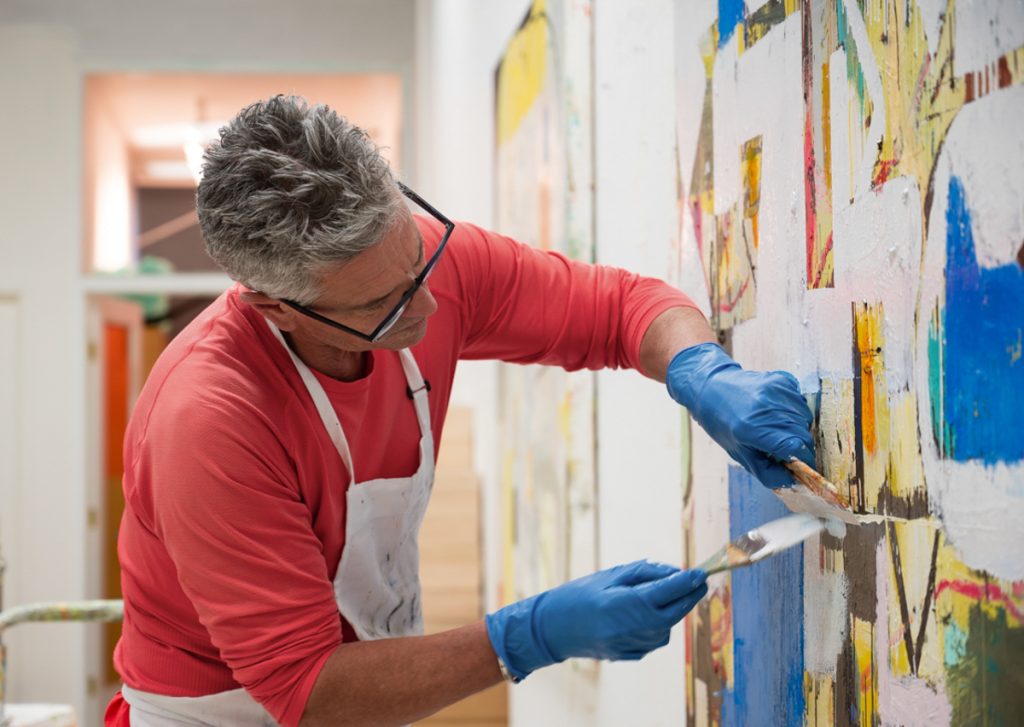 Artist working on a colorful abstract painting in his studio