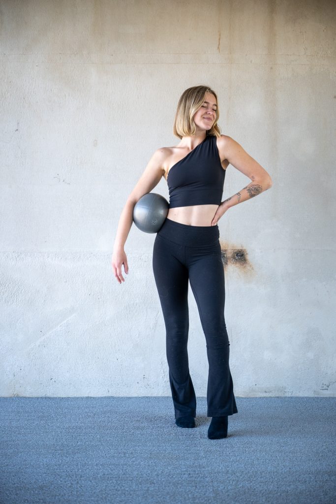 Fitness instructor holding a Pilates ball in a bright studio